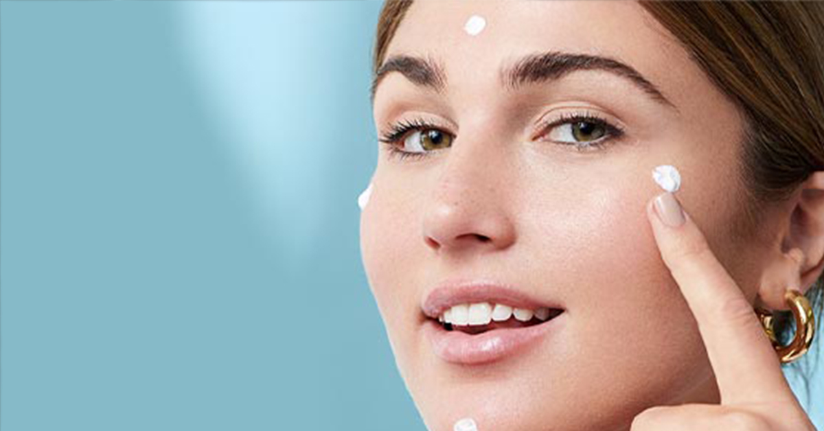 mujer aplicandose crema suero en el rostro en puntos especificos con fondo blanco