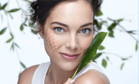 mujer usando crema facila bio resist con naturaleza, hojas a su alrededor, tecnologia innovadora